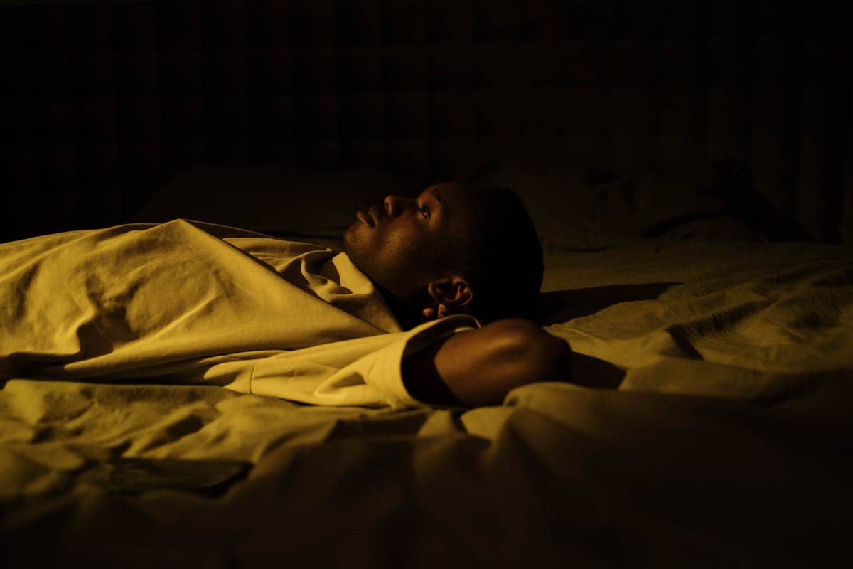 Homme allongé dans le noir, yeux ouverts, en réflexion