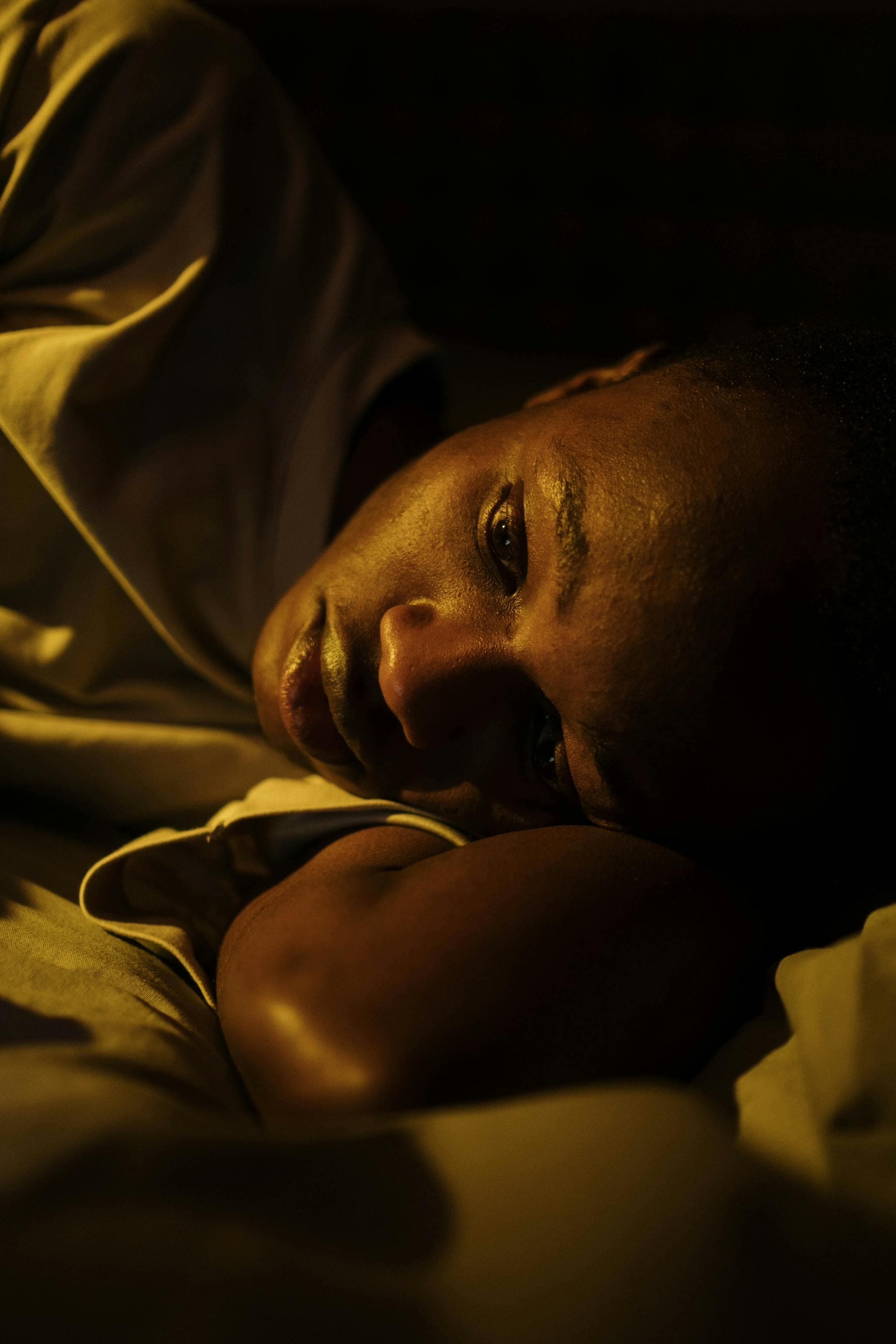 Jeune homme allongé dans le noir, insomniaque, les yeux ouverts dans l'obscurité